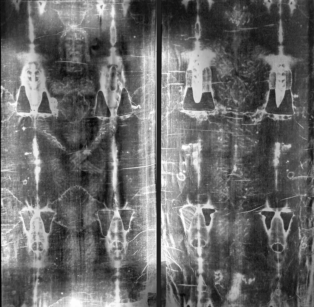 Two full-length negative prints of the Shroud displayed side by side in a church.