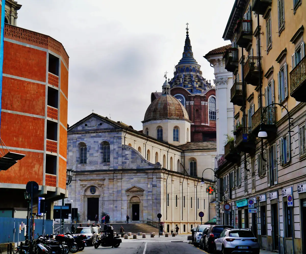 The marble front of Turin Cathedral with the dome of the Chapel of the Holy Shroud rising behind it.